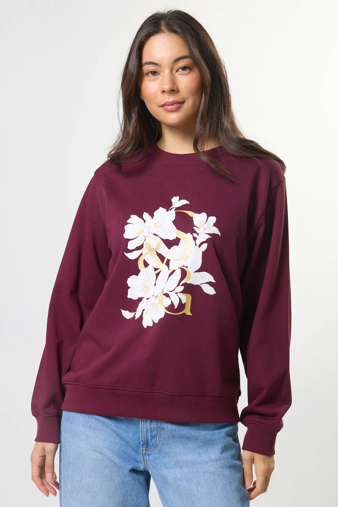 Woman wearing a burgundy sweatshirt with a floral design on a white background