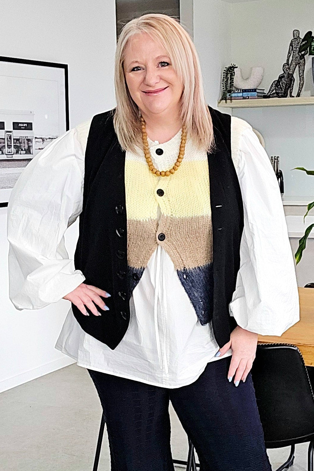 Woman standing in a modern office space with plants and furniture.