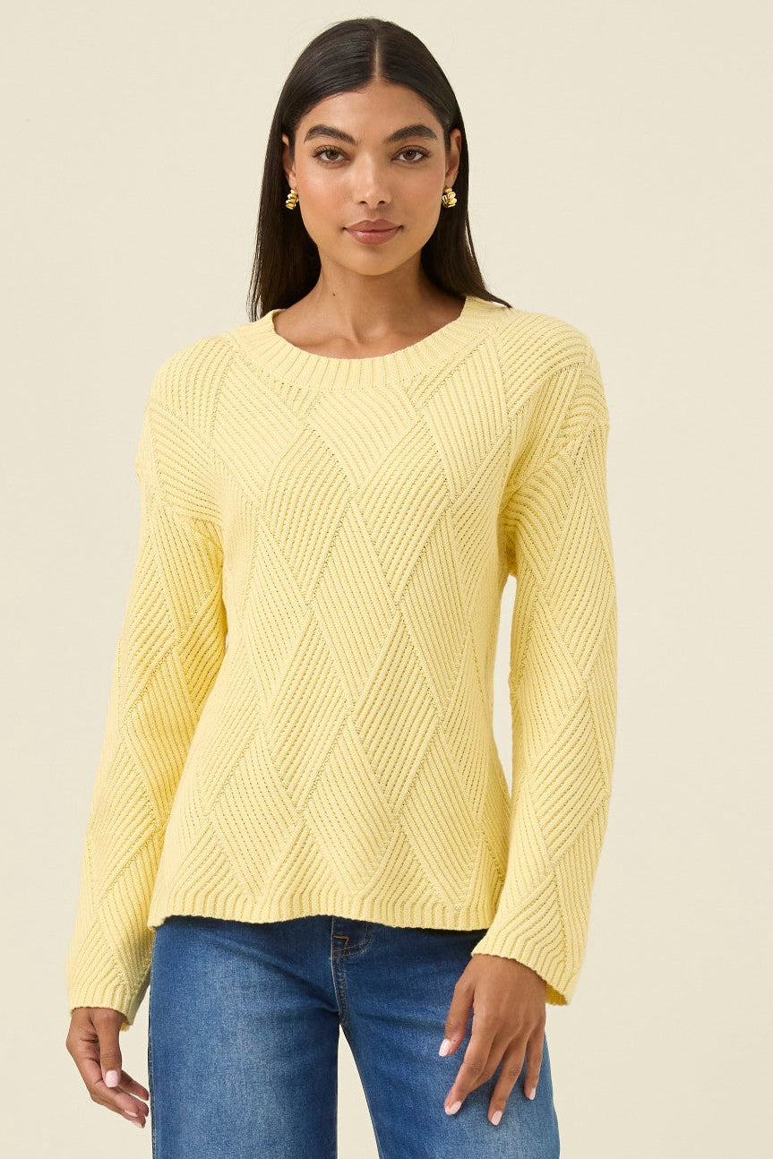 Woman wearing a yellow sweater and blue jeans on a beige background