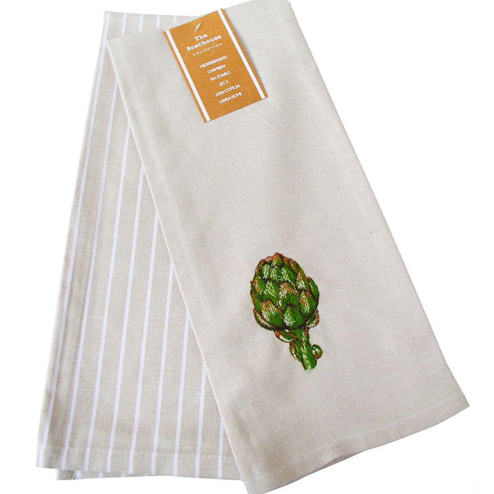 A folded beige kitchen towel with white vertical stripes on one side and a green embroidered artichoke on the other, featuring a tan paper label at the top.