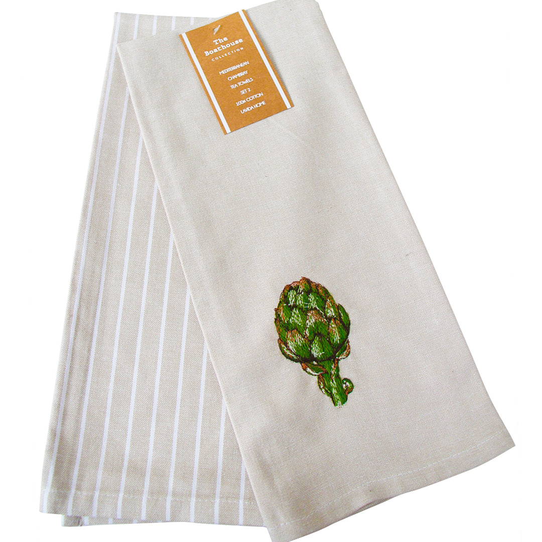 A folded beige kitchen towel with white vertical stripes on one side and a green embroidered artichoke on the other, featuring a tan paper label at the top.