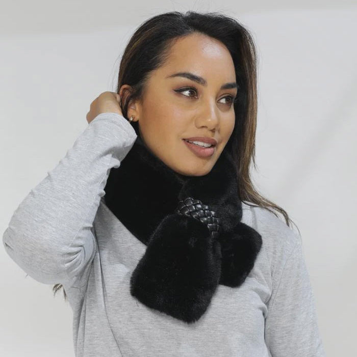Woman wearing a black fur scarf with a plain background
