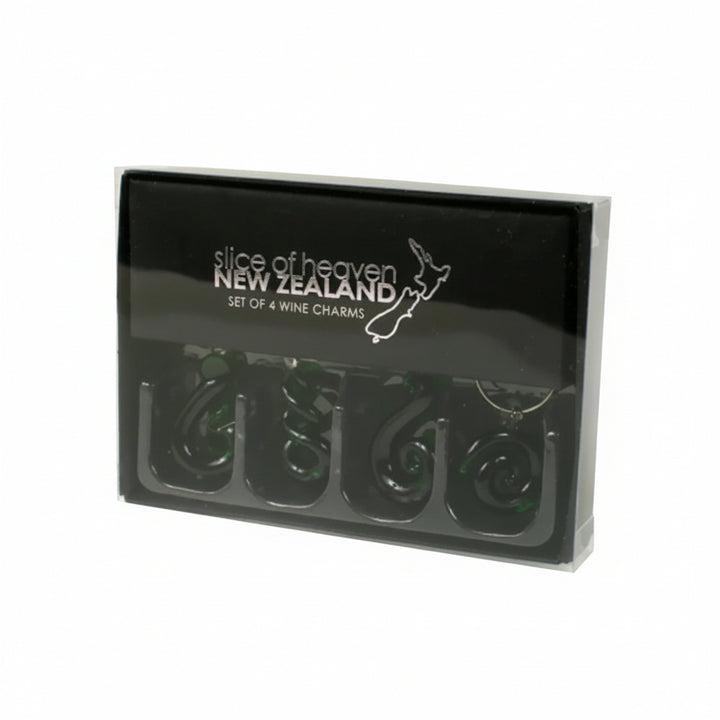A black gift box containing four dark green spiral-shaped wine charms, with 'slice of heaven NEW ZEALAND' printed in white on the lid.