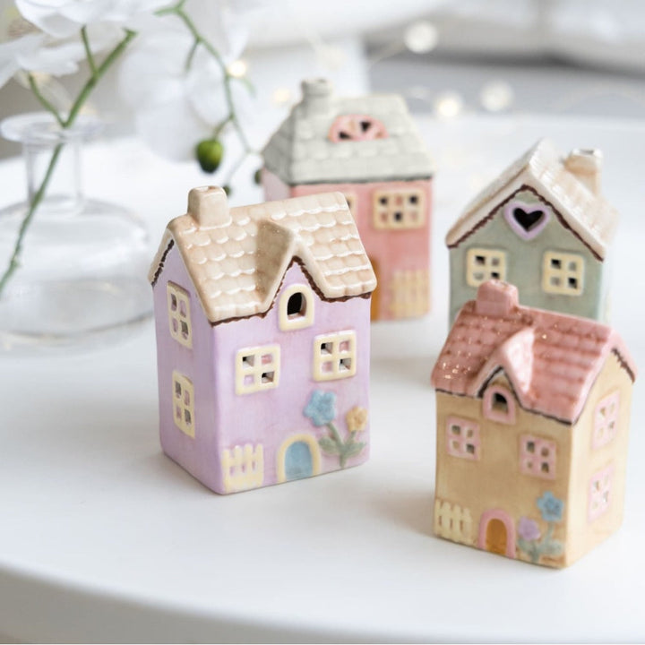 Set of small ceramic houses in pastel colors on a white surface.