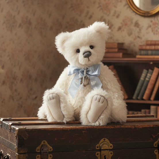 White charlie bears collectable teddy bear with a blue bow and decorative element on a trunk in a vinatge room