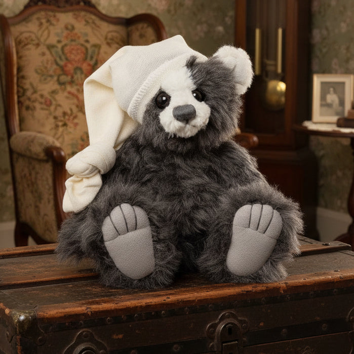 Plush bear charlie bears collectable toy with a white hat on a trunk in a bintage room