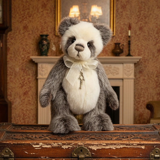 Stuffed charlie bears collectable panda bear with a bow and key charm on a trunk in a vintage room