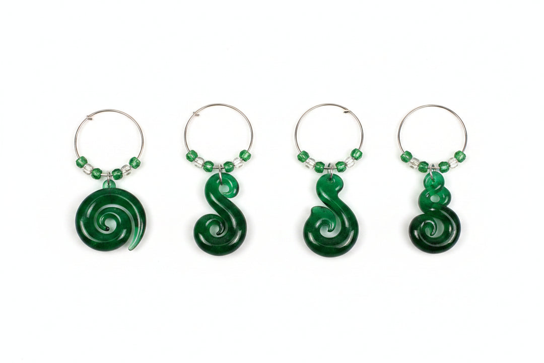 A set of four green wine charms in a black presentation box labeled 'slice of heaven NEW ZEALAND', with a smaller inset showing the charms hanging on hooks against the box.