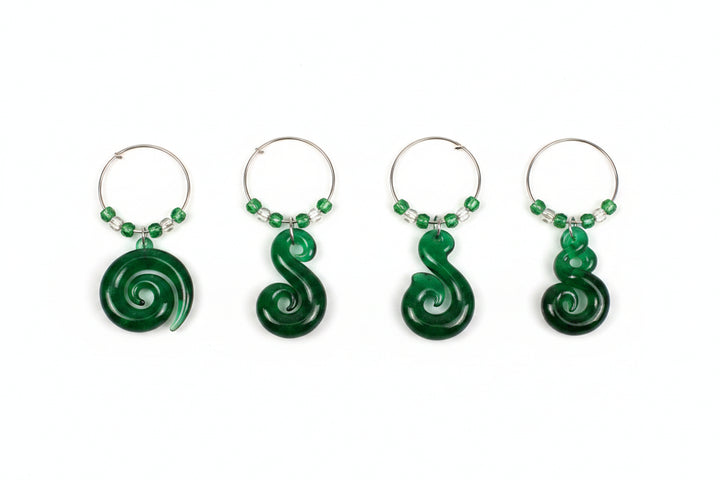 A set of four green wine charms in a black presentation box labeled 'slice of heaven NEW ZEALAND', with a smaller inset showing the charms hanging on hooks against the box.