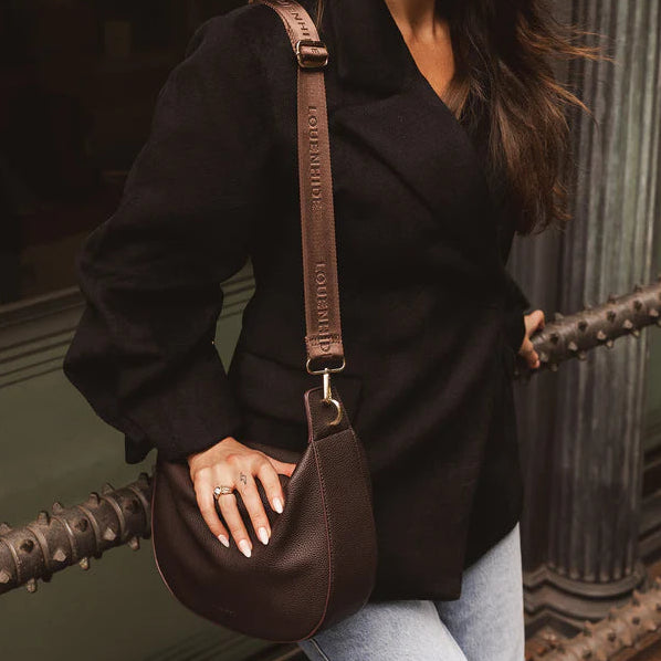 Woman holding a brown leather bag in an urban setting