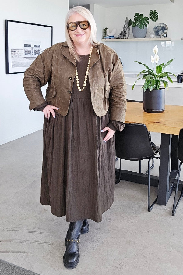 Person in a stylish outfit standing in an indoor setting with modern decor.
