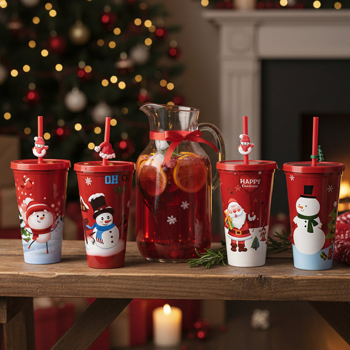 Six red Christmas-themed plastic cups with lids and straws, each decorated with different holiday illustrations including Santa Claus, snowmen, a penguin, and a rainbow. The cups are arranged on a plain white background.