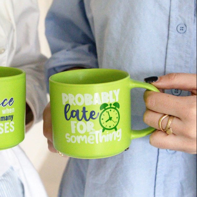 Two people holding green mugs with humorous text designs.