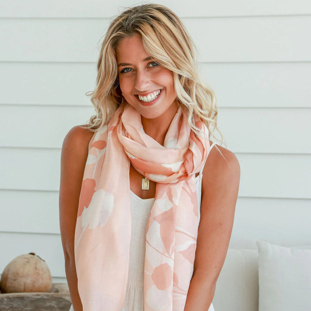 Woman wearing a light pink floral scarf in a casual setting.