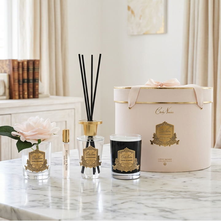 Set of decorative items including a diffuser, candle, and packaging with branding on a white background.