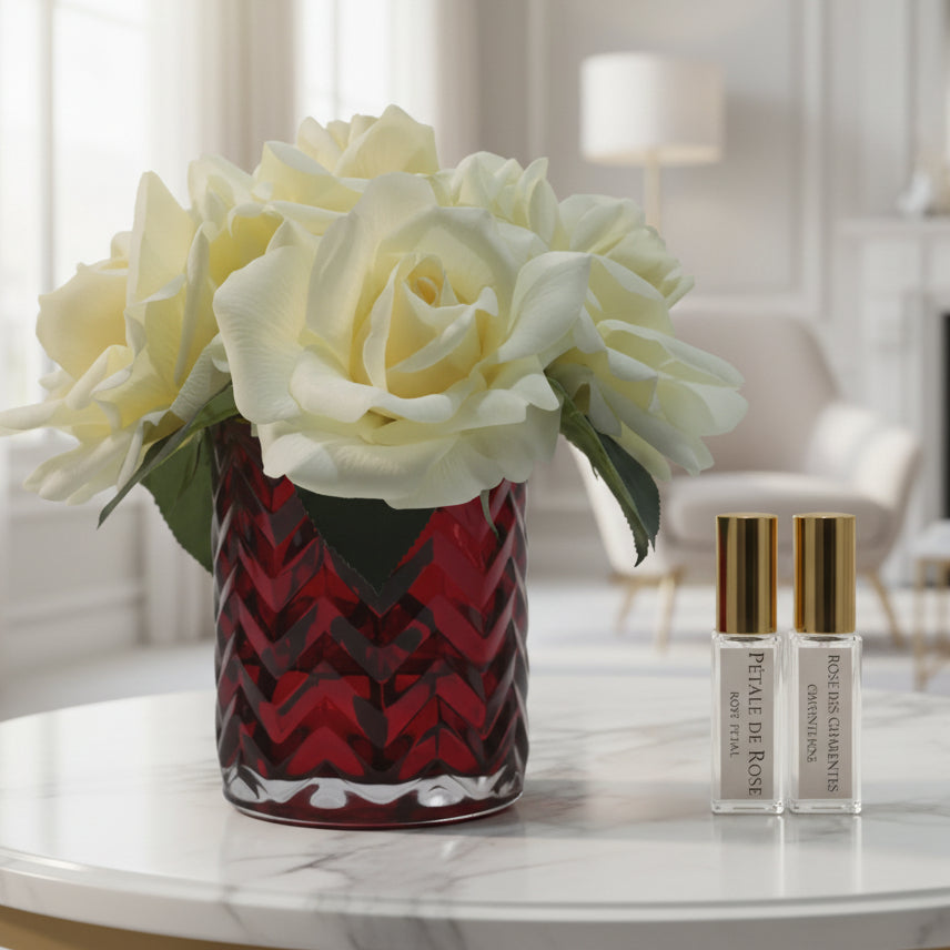 Decorative vase with white flowers and two perfume bottles on a light gray background