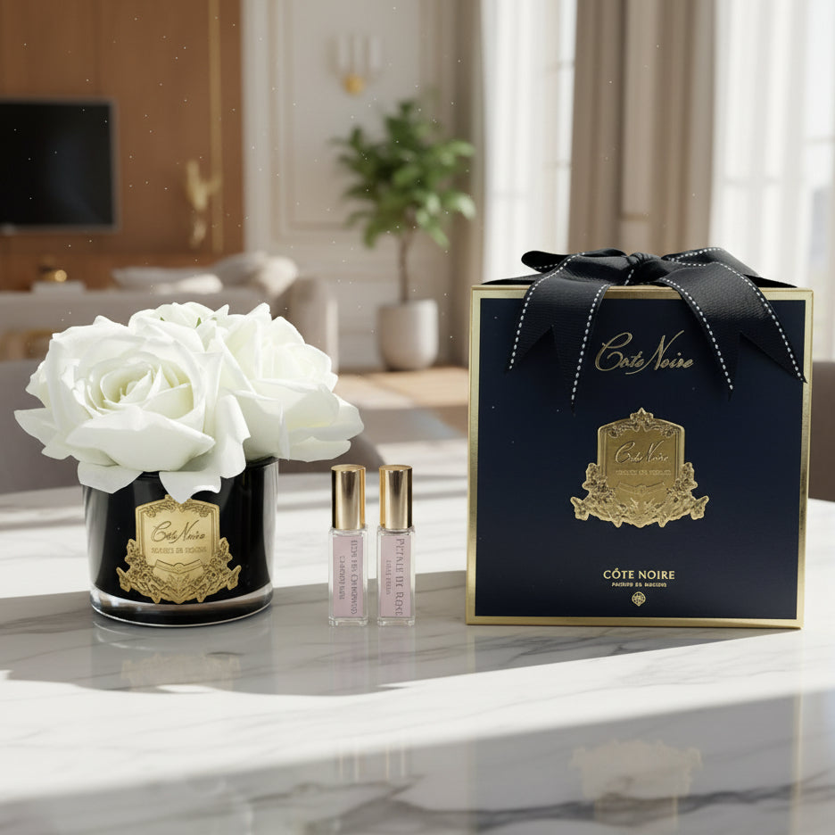 Cote Noire perfume set with black box, white flowers, and two small bottles on a white background