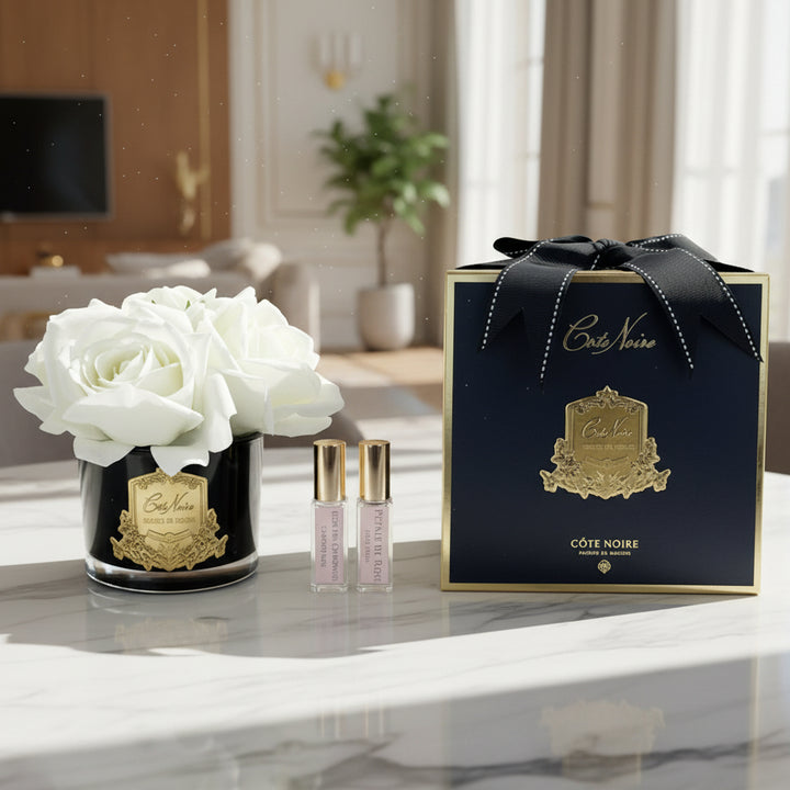 Cote Noire perfume set with black box, white flowers, and two small bottles on a white background