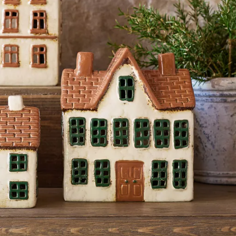 Set of ceramic house-shaped boxes on a wooden surface with a stone wall background