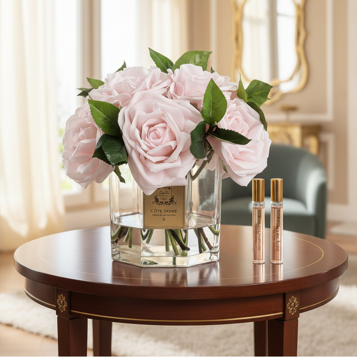 Cote Noire floral arrangement in a glass vase with two perfume bottles in a luxurious room.
