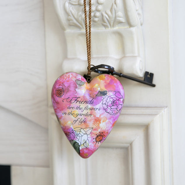 Heart-shaped decorative plaque with floral design and text on a white wall.