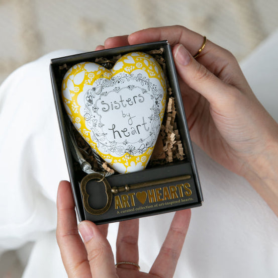 Heart-shaped object with 'Sisters' at the center, held in a box labeled 'Art Hearts'.