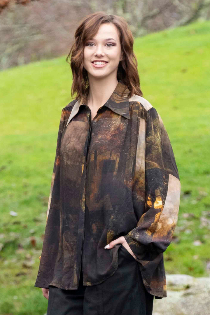 Woman standing by a pond in a park with green grass and trees wearing a Deeanne Hobbs Buccaneer Shirt.