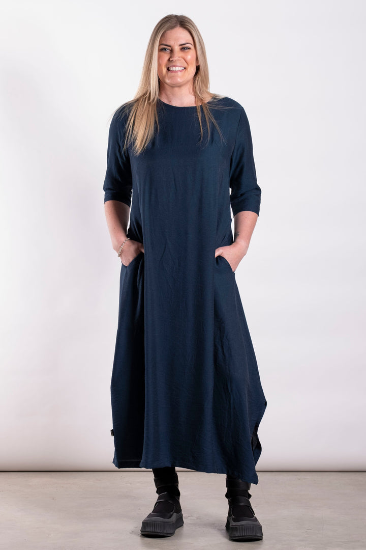 Woman wearing a long navy dress against a white background