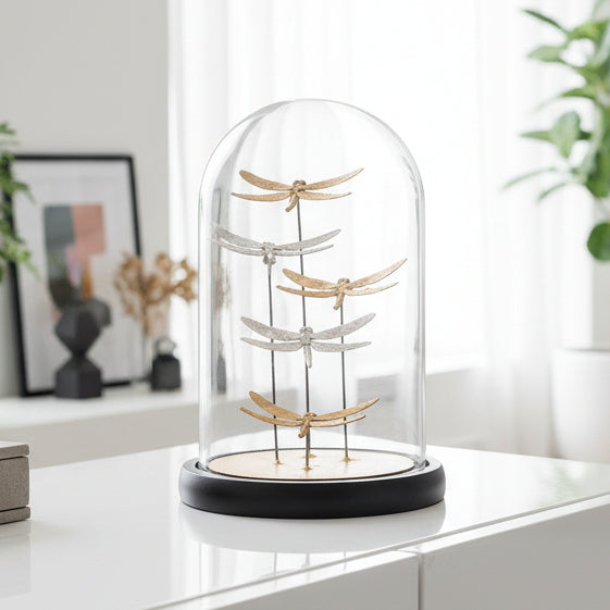Decorative glass dome with gold and silver dragonfly figurines on a white background