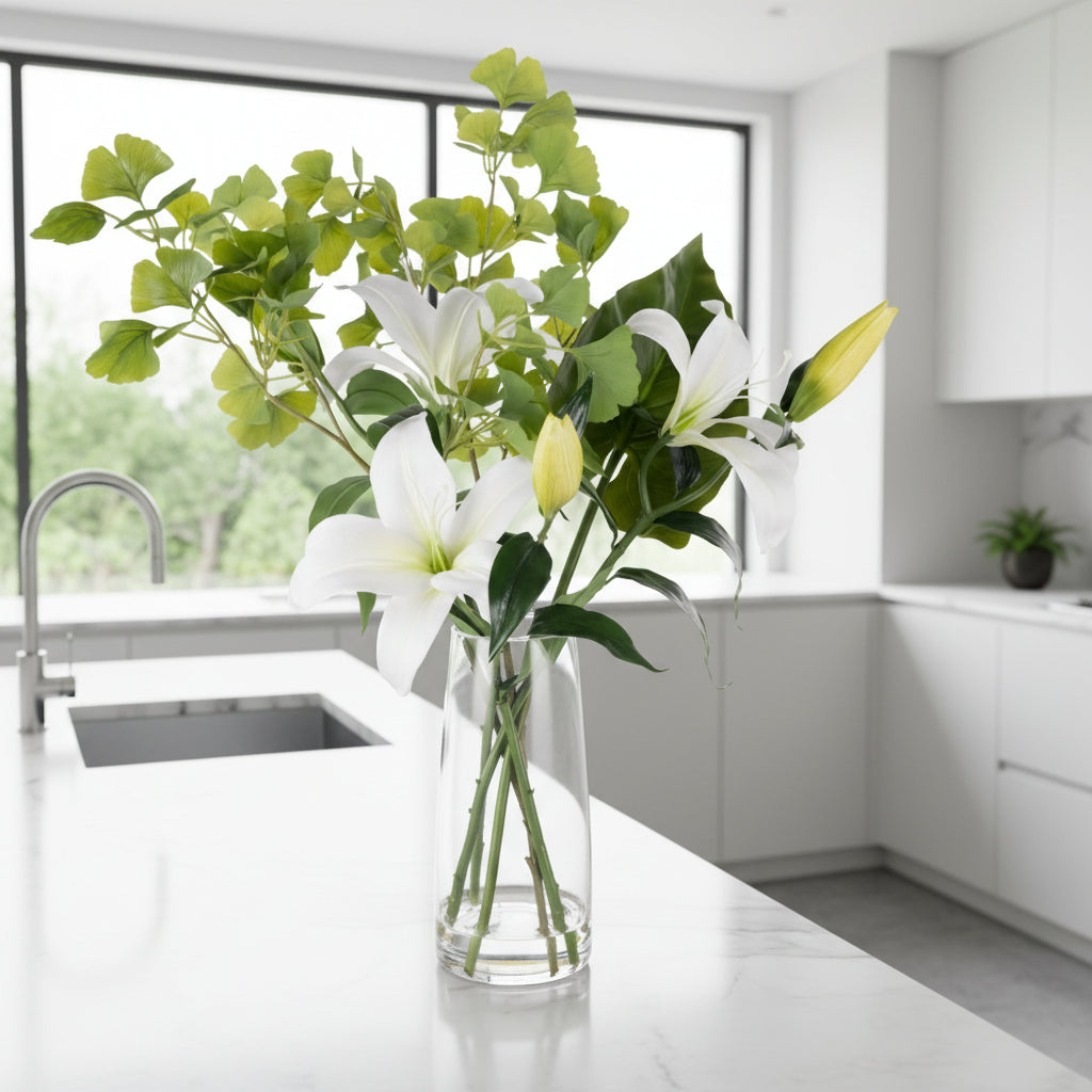 Clear glass vase with white lilies and green leaves on a white background