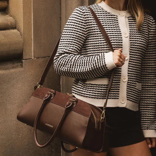 Woman holding a brown leather bag against a building background