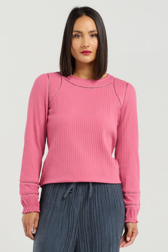 Woman wearing a pink sweater and blue pants on a white background
