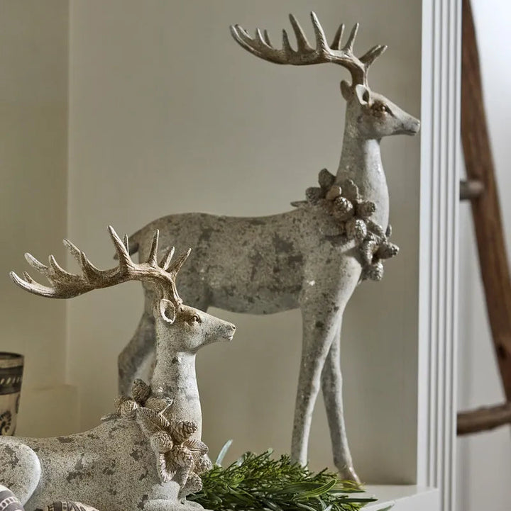Decorative deer statues with antlers and foliage on a neutral background
