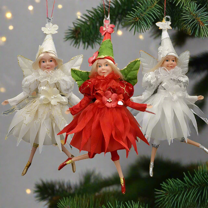 Three fairy figurines in red, green, and white dresses on a white background