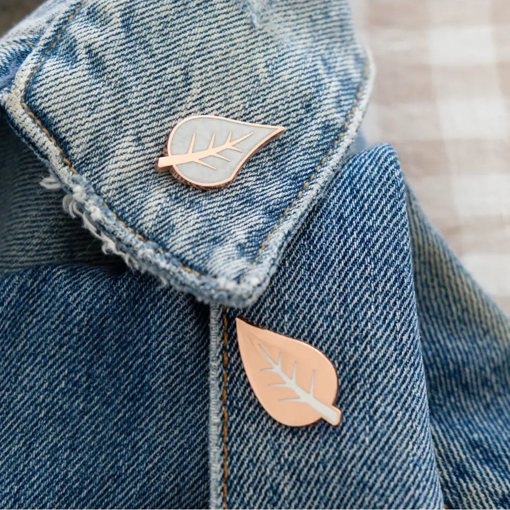 Two leaf-shaped pins on a denim jacket