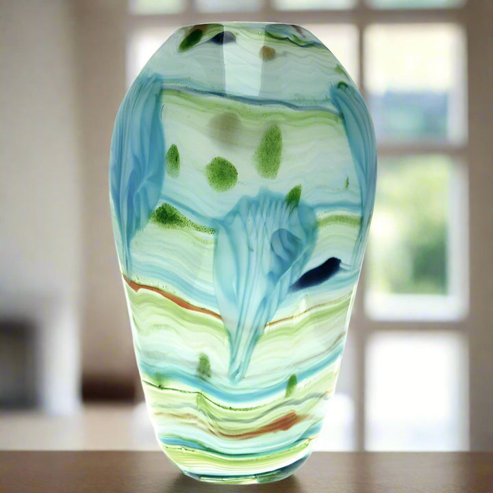Glass vase with blue and green patterns on a white background