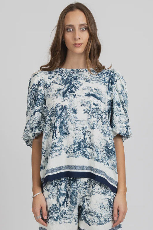 Woman wearing a blue and white patterned outfit on a gray background