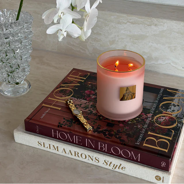 Pink candle burning on a stack of books with white flowers in the background