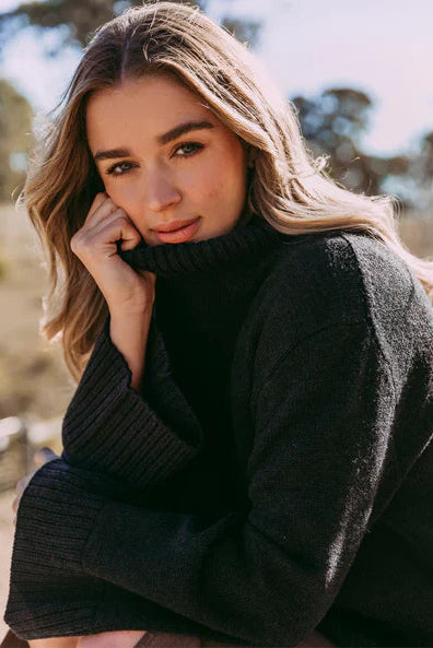 Woman wearing a black sweater outdoors with blurred background