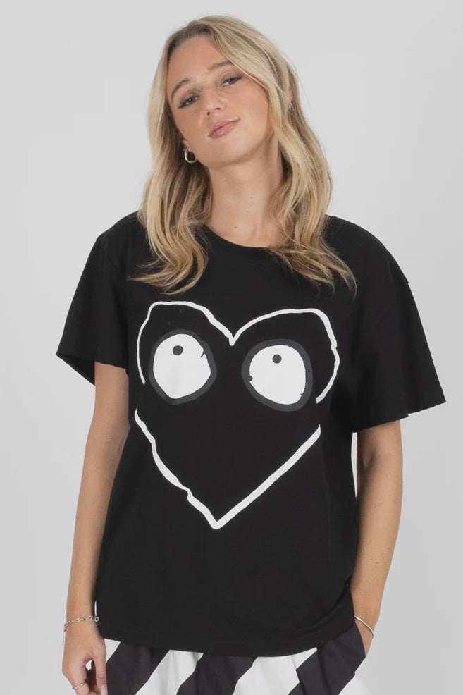 Woman wearing a black federation t-shirt with a white heart design on a plain background