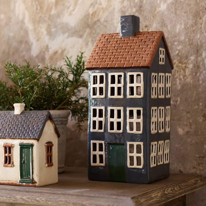 Decorative ceramic house models on a wooden surface with a textured wall background