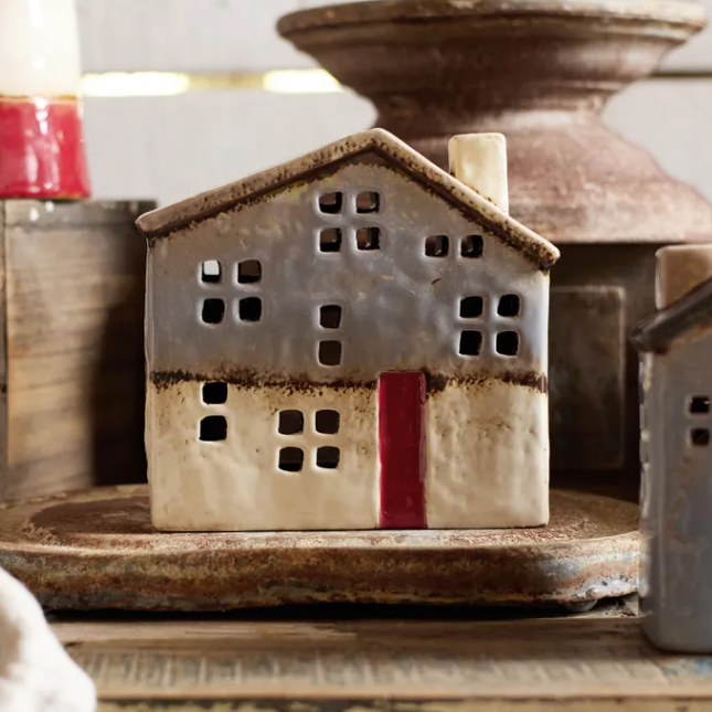 Decorative ceramic house with a red door on a rustic surface