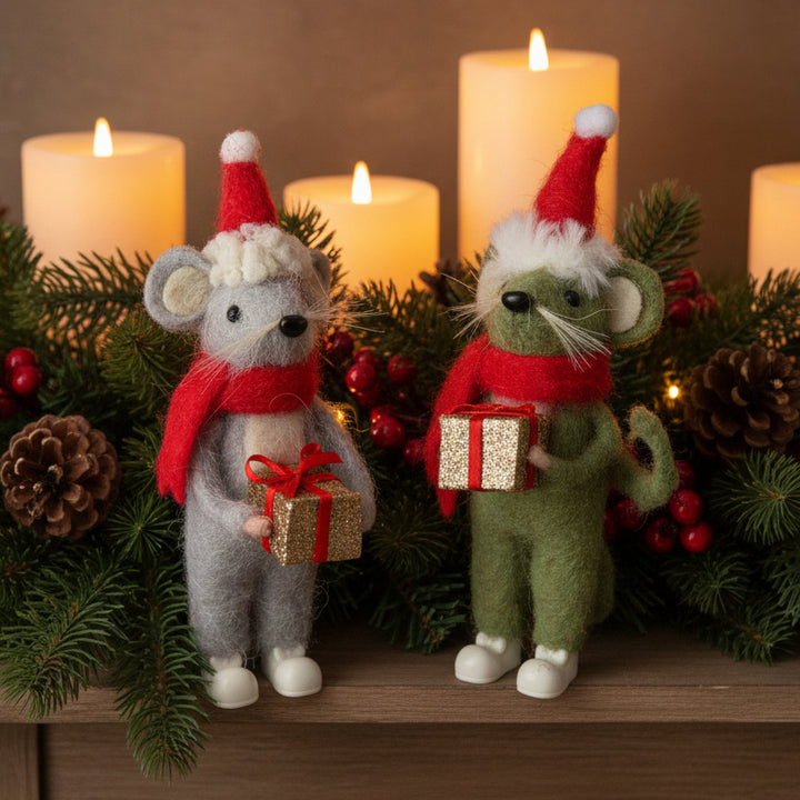 Two felted animal figurines, one gray and one green, dressed in Santa hats and scarves while holding small glittery gift boxes, photographed against a xmas background