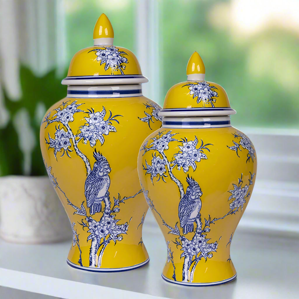 Two yellow ceramic vases with blue floral and bird patterns on a white background