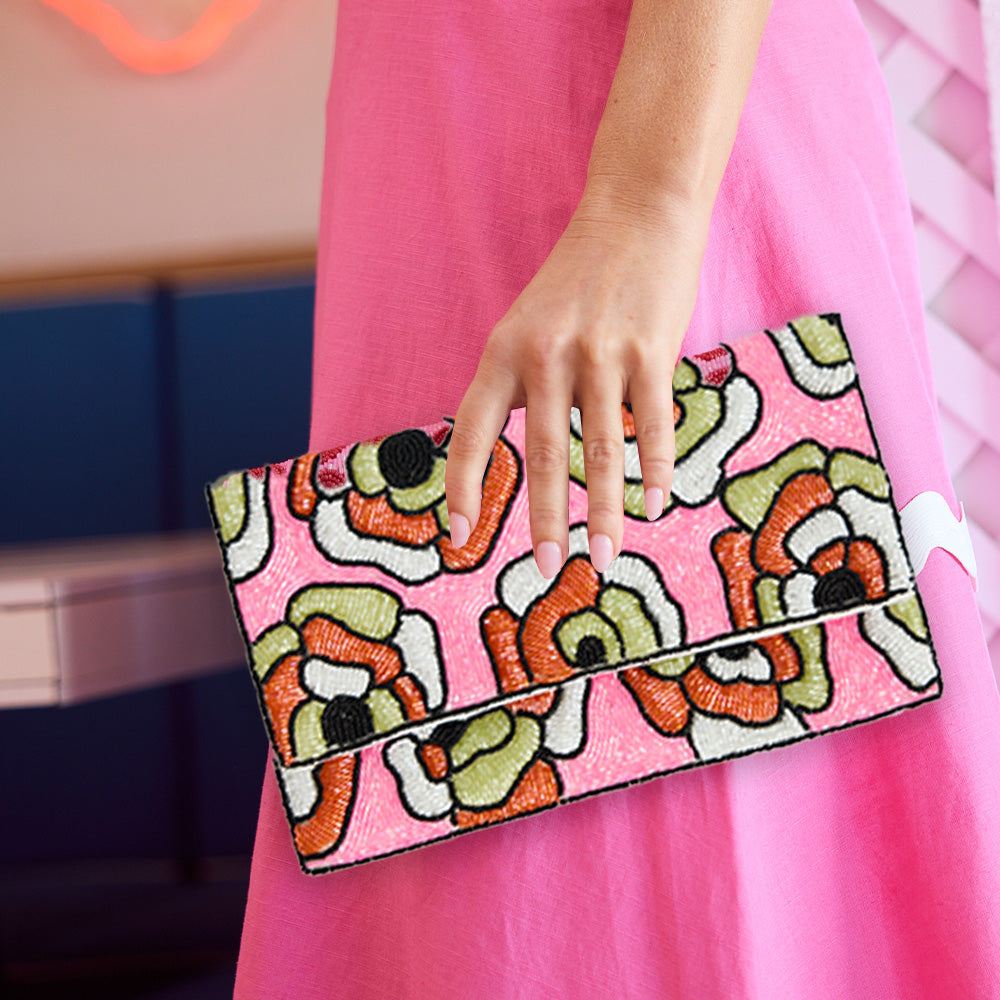 Hand holding a colorful clutch with a pink background
