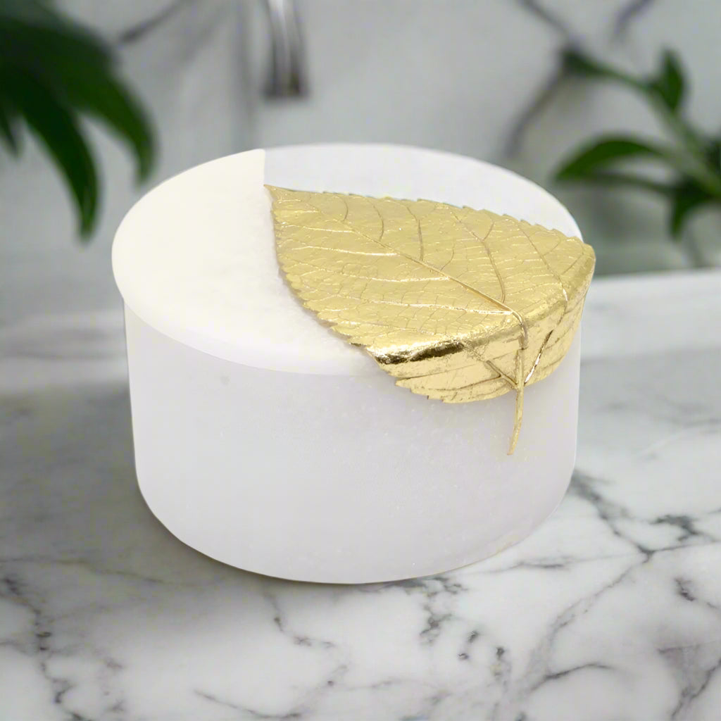 White round box with a gold leaf on a white background