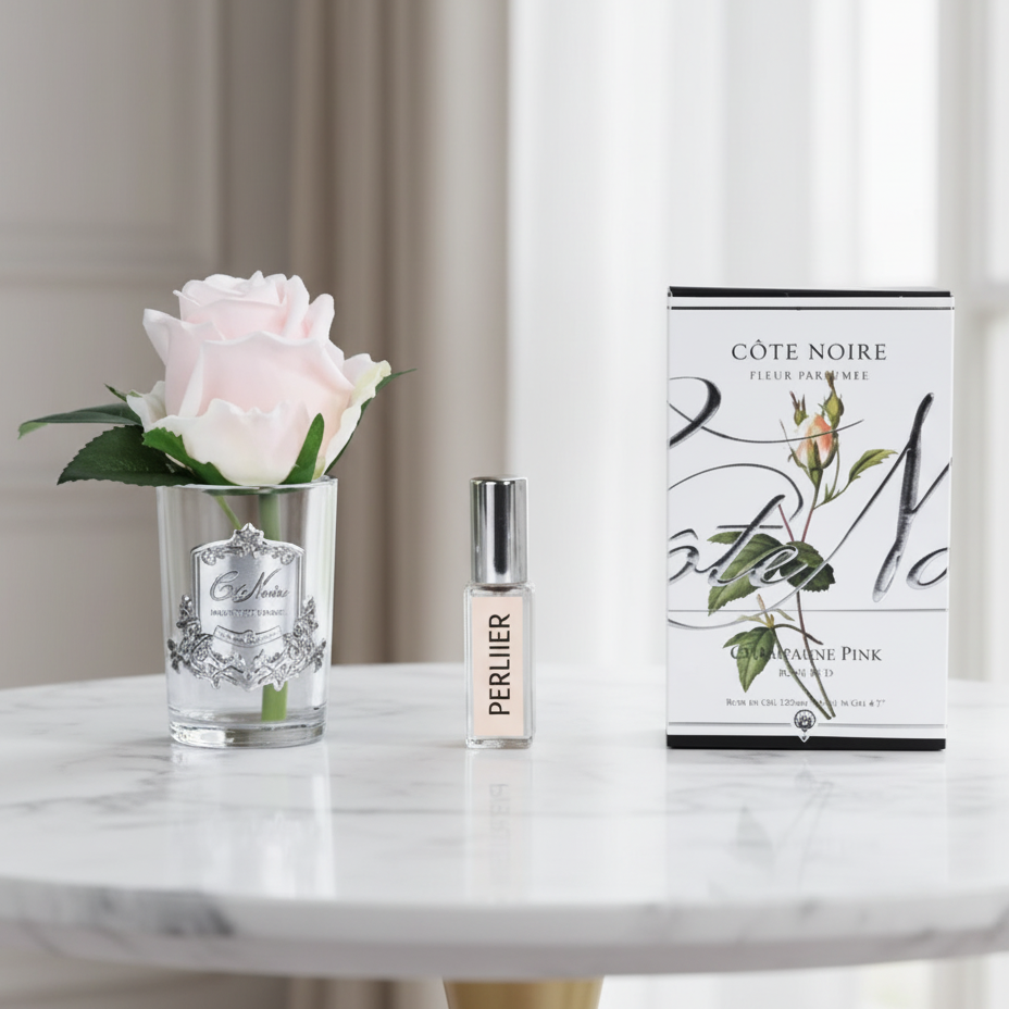 Cote Noire Set with a pink rose in a glass, a small bottle of perfume, and a box labeled 'Côte Noire' in a luxury room.