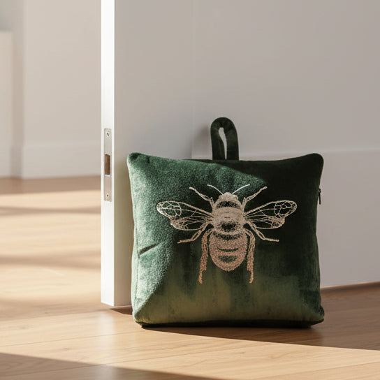 Green velvet doorstop with a bee design on a white background
