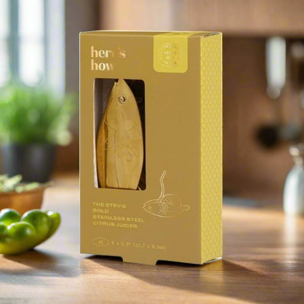 Gold citrus juicer in a 'here's how' branded box on a white background