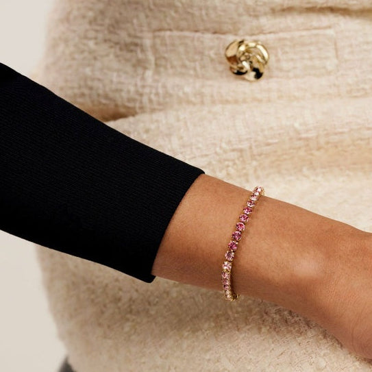 Person wearing a pink beaded bracelet on a neutral background